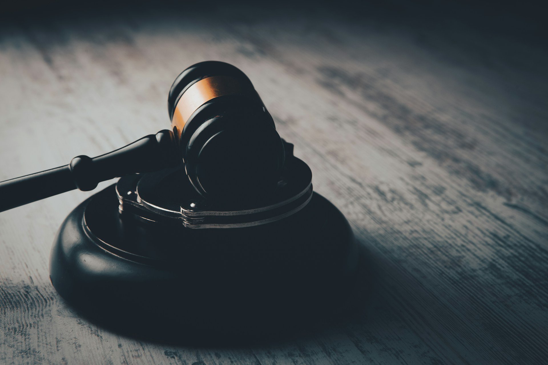 A judge's gavel and handcuffs on a wooden table