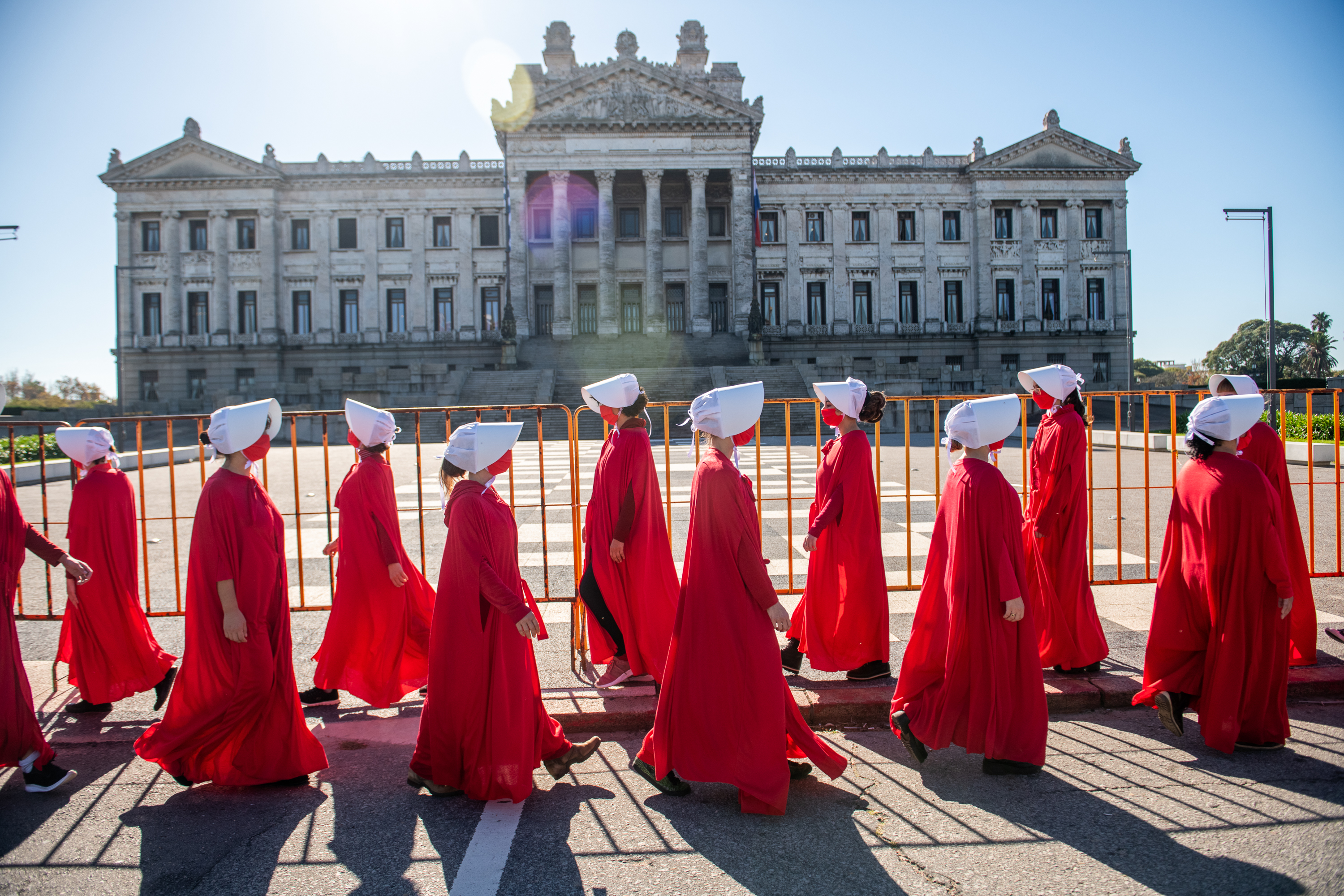 Demonstrators in red robes and white bonnets march past the Legislative Palace in Montevideo
